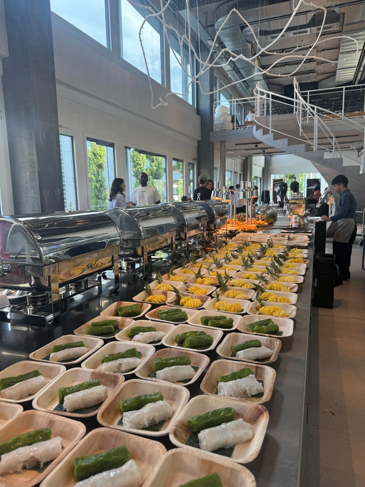 Catering-Buffet mit Chafing Dishes und vietnamesischen Desserts auf Palmblatt-Schalen